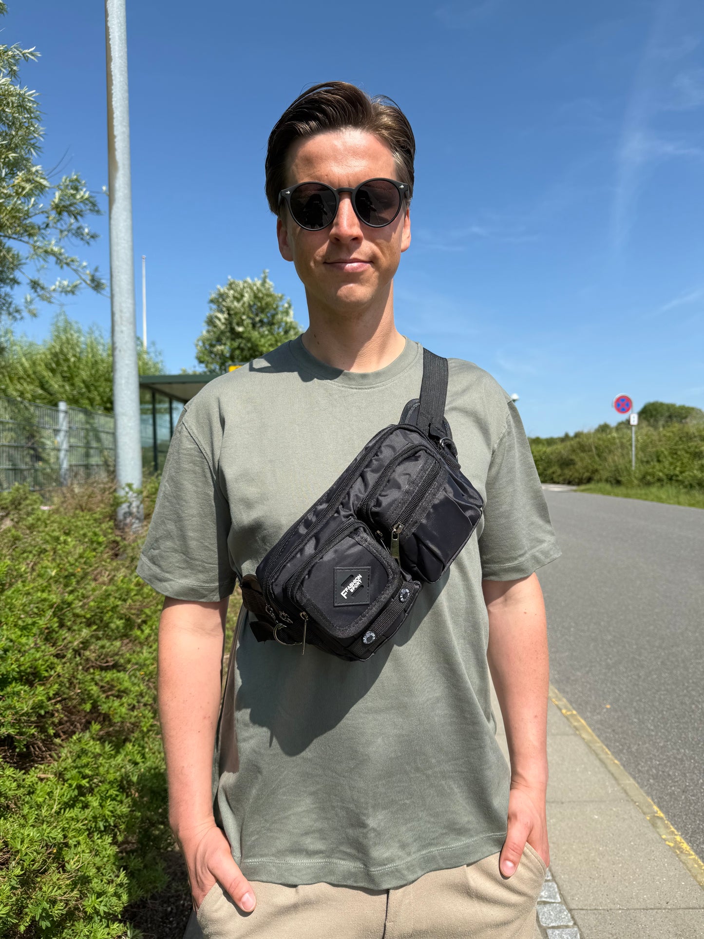 Mandlig model bærer bæltetasken i sort som crossover på forsiden.