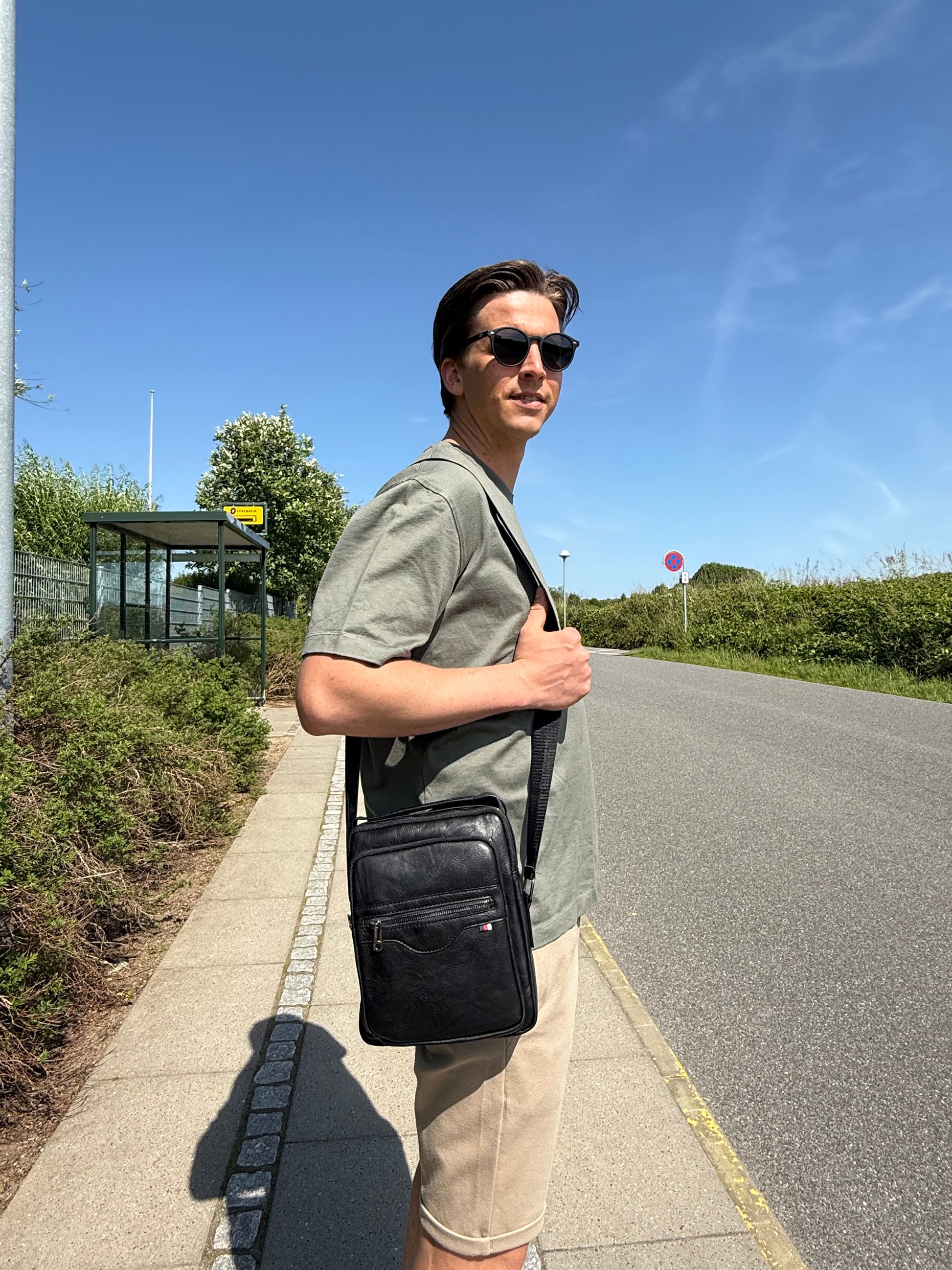 Mandlig model bærer Unisex Messenger Taske i sort over skulderen.