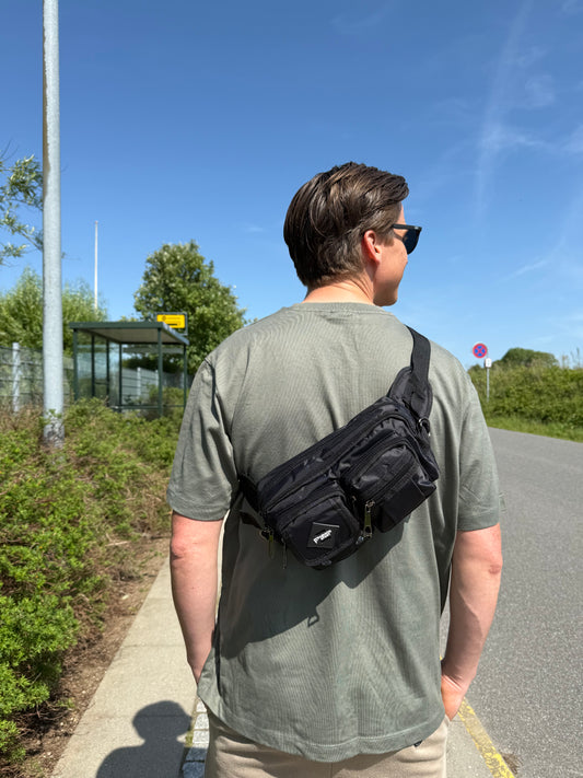 Mandlig model bærer bæltetasken i sort som crossover på ryggen.