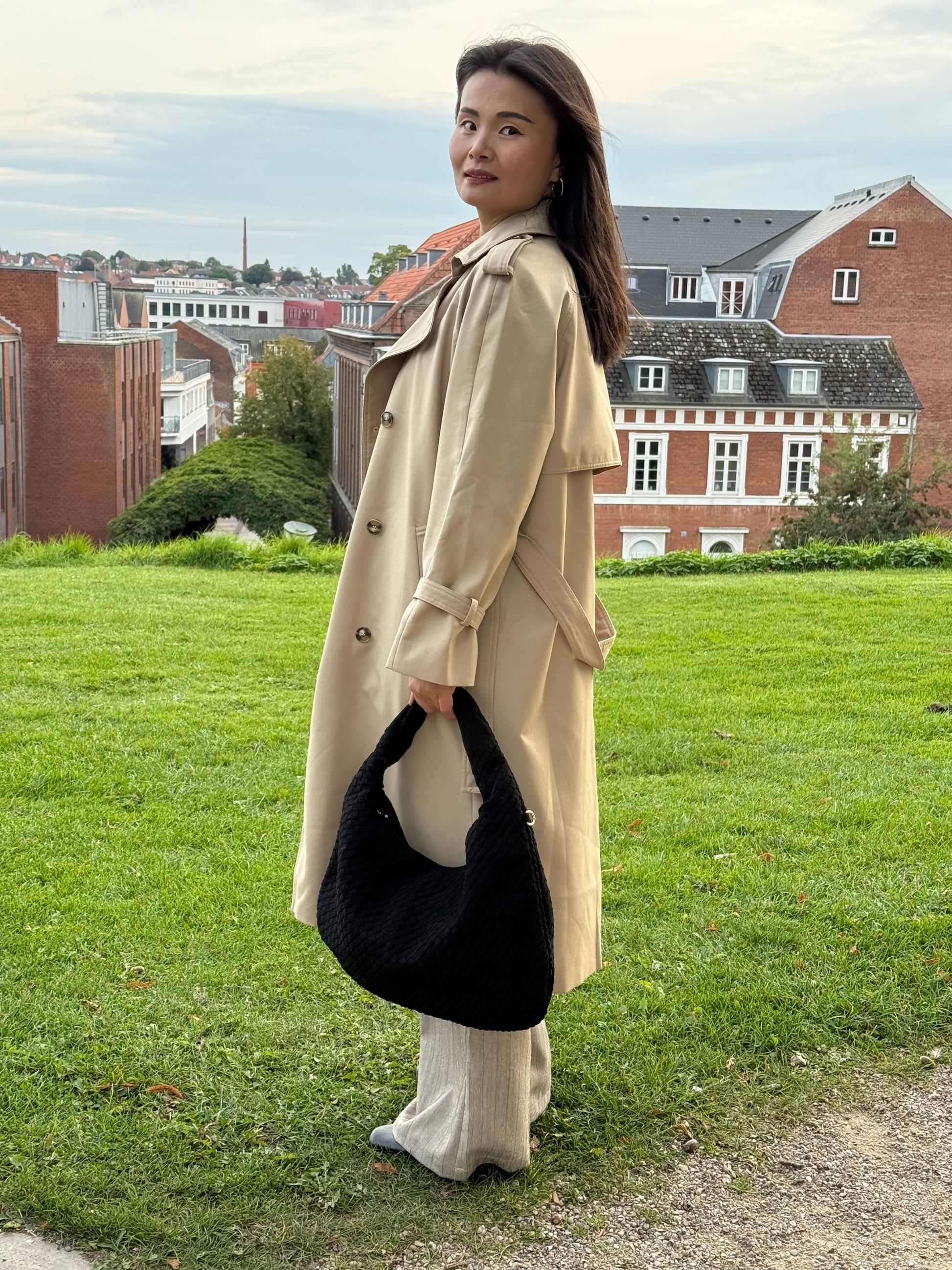 Model holder Anna Fake Suede flettet skuldertaske i sort fra MAS SELECTION i den ene hånd