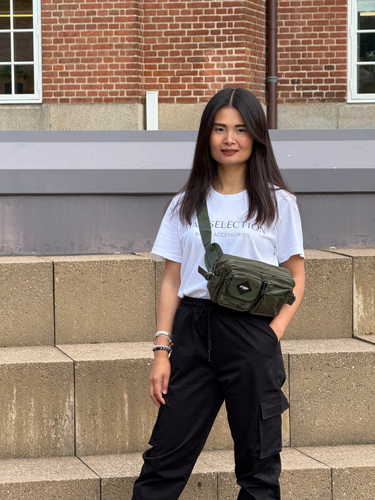 Kvindelig model bærer bæltetasken i grøn som crossover på forsiden.