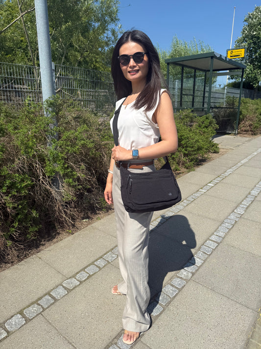 Model med Asta skuldertaske i sort som crossover – viser pasform og stil