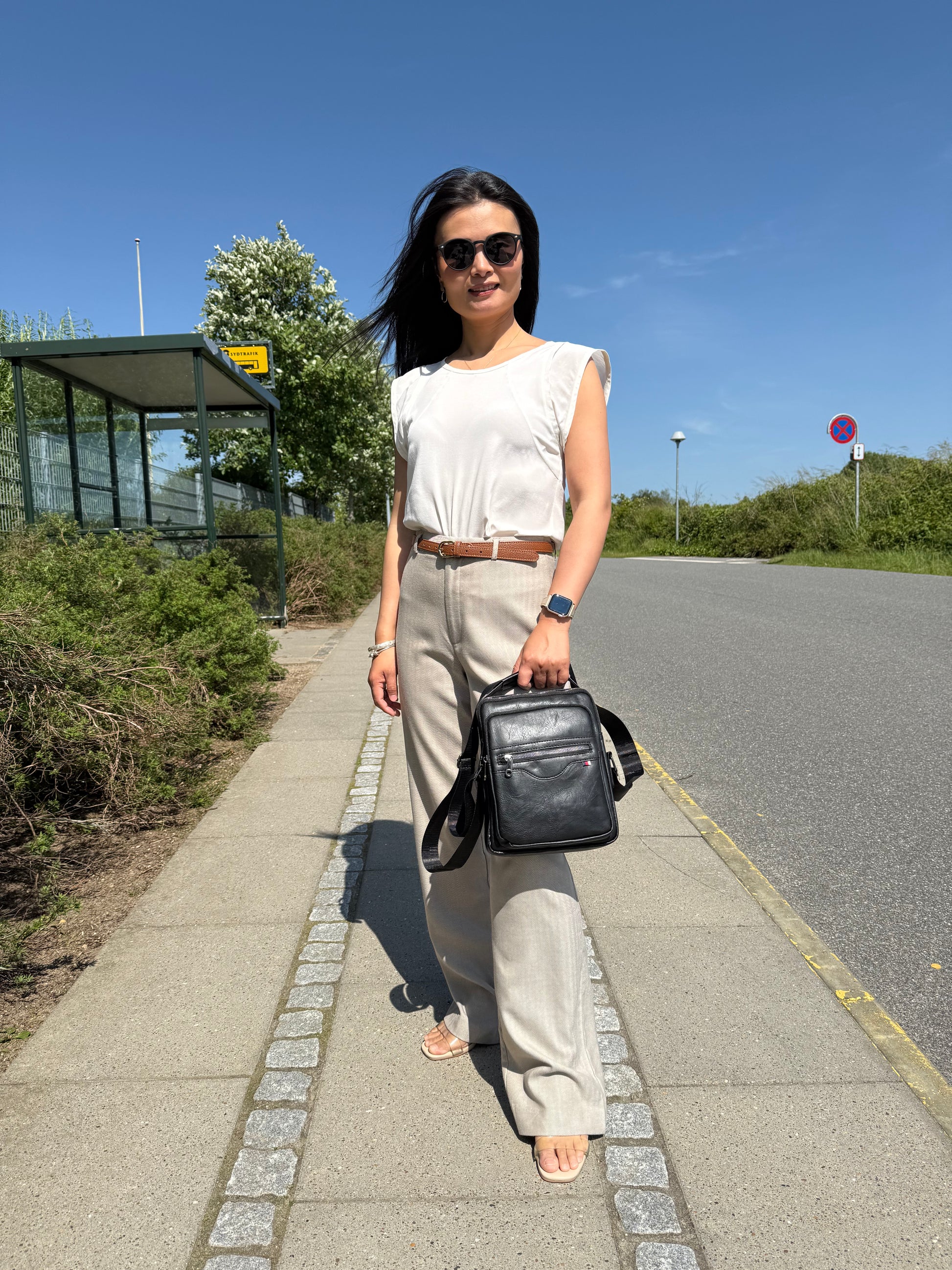 Kvindelig model holder Unisex Messenger Taske i sort i hånden.