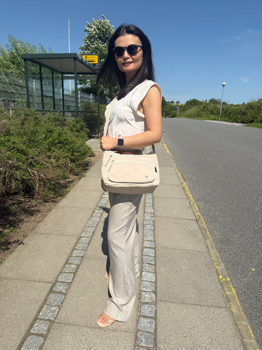 Model med Asta skuldertaske i beige som crossover, der viser pasform og stil.
