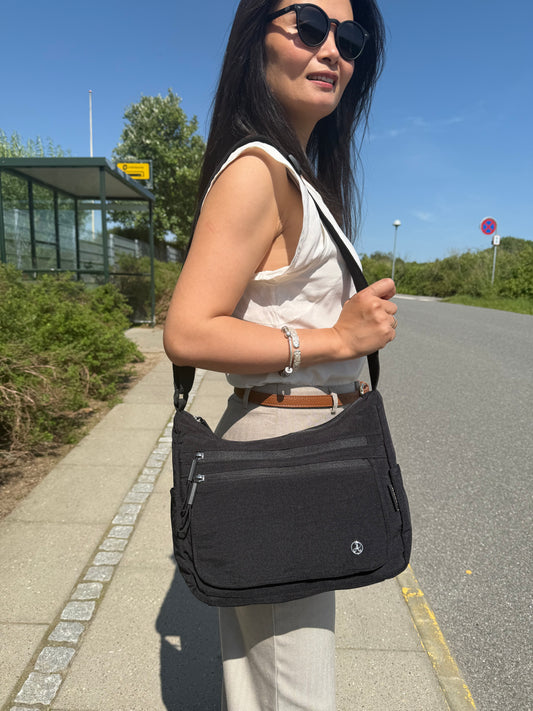 Model med Asta skuldertaske i sort over skulderen – viser taskens størrelse