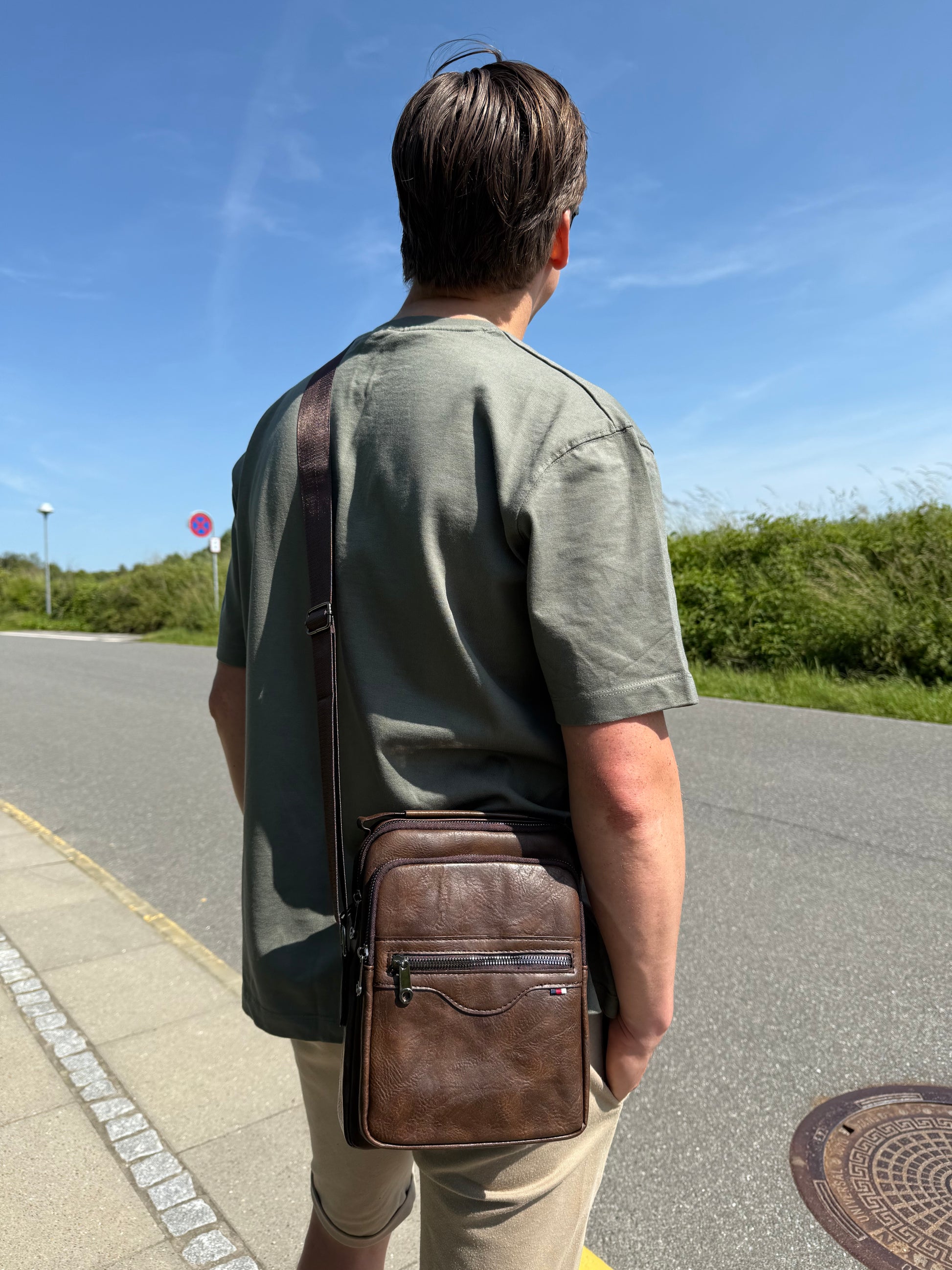 Mandlig model bærer Unisex Messenger Taske i mørkebrun som crossover.