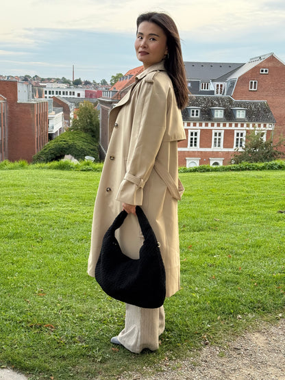 Model holder Anna Fake Suede flettet skuldertaske i sort fra MAS SELECTION i den ene hånd
